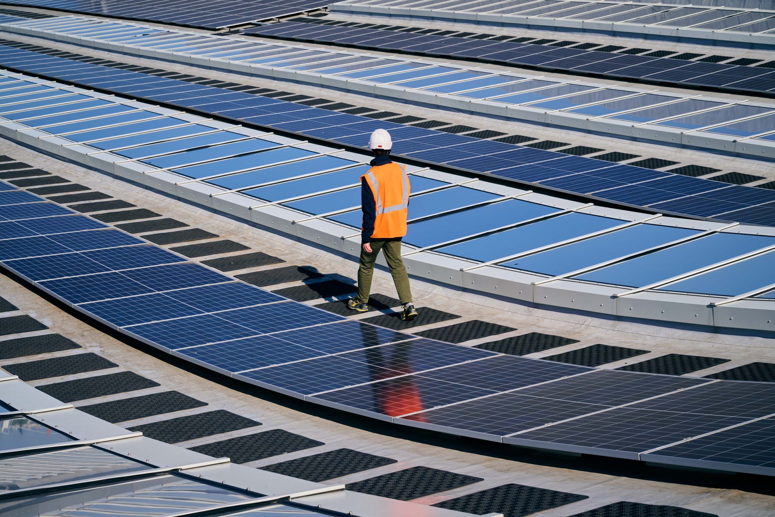 Conducteur de travaux au milieu des panneaux photovoltaïque sur le toit du centre aquatique olympique Paris 2024